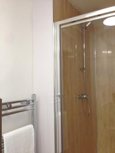 La salle de bains est pourvue d'une douche avec une porte en verre. dans l'établissement Gallowgate Square Apartments, à Largs