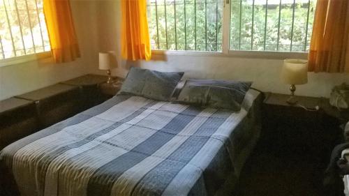 a bed in a bedroom with two windows at Chalet Panda in Pinamar