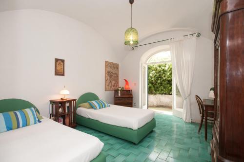 ein Schlafzimmer mit zwei Betten und einem Tisch und einem Fenster in der Unterkunft Casa Giardino in Positano