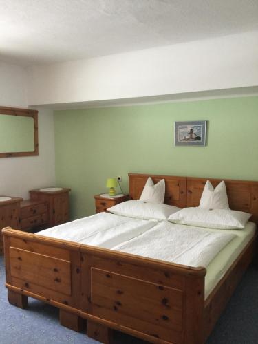 Un dormitorio con una gran cama de madera con sábanas blancas. en Ferienwohnung Sonnschein, en Bad Mitterndorf