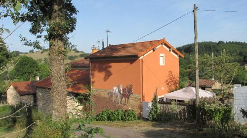 une maison orange avec un cheval peint sur elle dans l'établissement La vache sur le toit, à Montagny