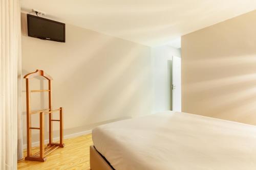 a bedroom with a bed and a tv on the wall at Berço de Mordomias in Braga