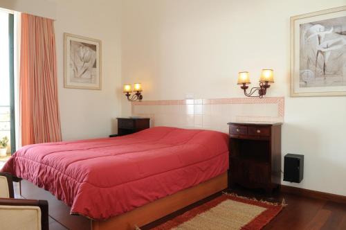 a bedroom with a red bed with a red blanket at Vivenda Belo Horizonte in Caniço