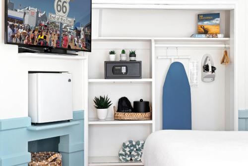 a bedroom with a bed and a tv and shelves at Sea Blue Hotel in Los Angeles
