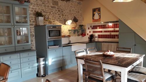 uma cozinha com armários azuis e uma mesa de madeira em Chateau Le Colombier em Brévands