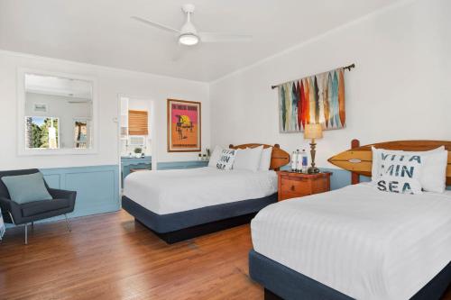 a hotel room with two beds and a chair at Sea Blue Hotel in Los Angeles