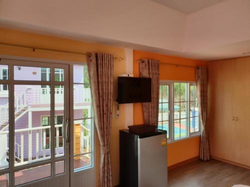 a room with a refrigerator and a balcony with windows at Bunny Hill Resort in Chon Buri