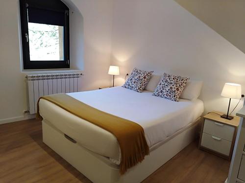 a bedroom with a bed with two lamps and a window at Ca de Géraldine in El Pont de Suert