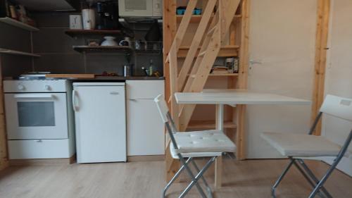 ル・ブール・ドアザンにあるStudio La Muzelle Bourg d'Oisansのキッチン(白い冷蔵庫、テーブル、椅子付)