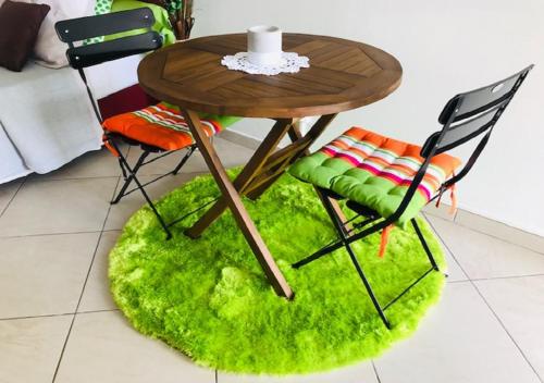 a table and chairs with a green rug under it at Vert Pays in Fort-de-France