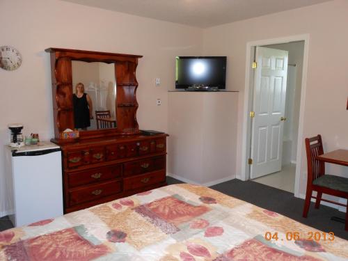 a bedroom with a dresser with a mirror and a television at Mountain Springs Motel & RV Park in Barrière