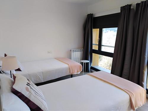 a hotel room with two beds and a window at Ca de Géraldine in El Pont de Suert
