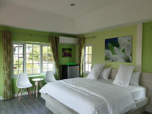 sypialnia z białym łóżkiem, zielonymi ścianami i oknami w obiekcie Bunny Hill Resort w mieście Chon Buri