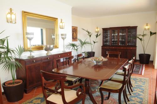 a dining room with a table and chairs and a mirror at Vivenda Belo Horizonte in Caniço