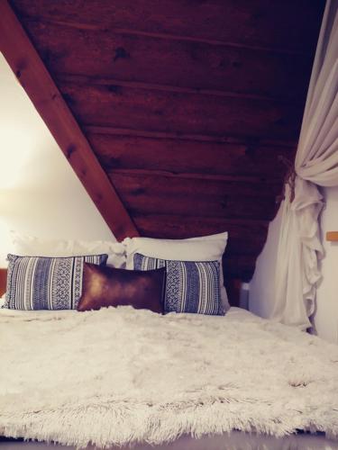 a bedroom with a white bed with a wooden ceiling at U Hanki in Biały Dunajec