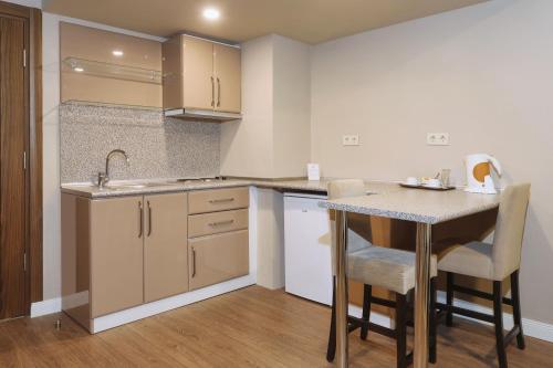 a kitchen with a sink and a table with chairs at New Balturk Hotel Izmit in Kocaeli