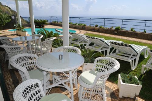 a patio with tables and chairs and the ocean at Vivenda Belo Horizonte in Caniço