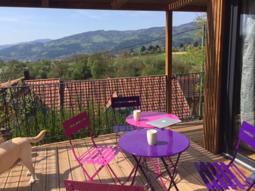 a patio with purple tables and chairs and a dog on a balcony at Loft "Home, Sauna & Pool" in Osenbach