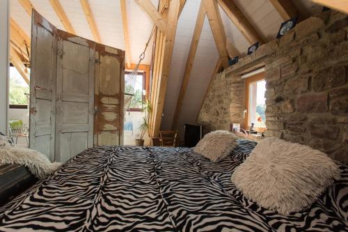 uma cama com estampa de zebra num quarto com uma parede de pedra em Loft "Home, Sauna & Pool" em Osenbach