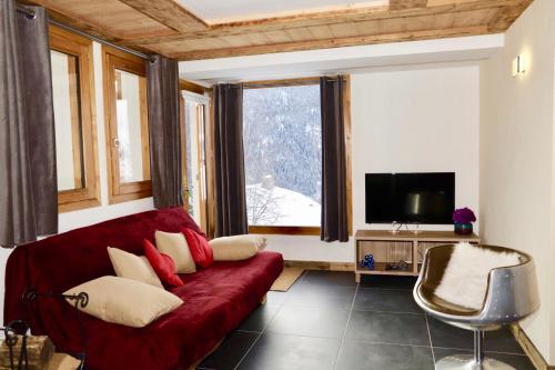 ein Wohnzimmer mit einem roten Sofa und einem Fenster in der Unterkunft Le Falyoucher in Peisey-Nancroix