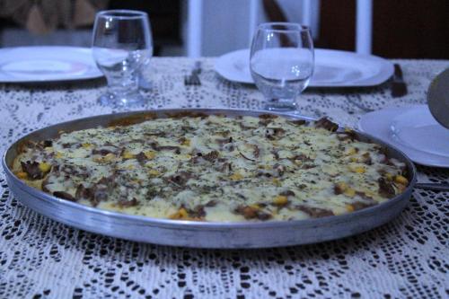 a pizza in a pan on a table with wine glasses at Pousada Felix in São Gabriel