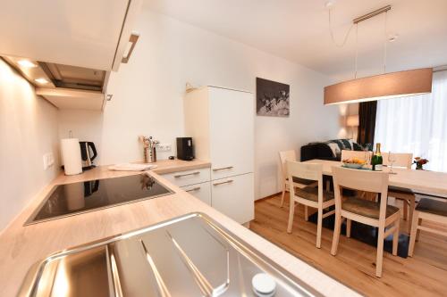 a kitchen with a sink and a table in a room at Salzgeber Appartements in Sankt Gallenkirch