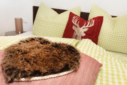 a bed with a comforter with a blanket and a pile of furidding at Salzgeber Appartements in Sankt Gallenkirch