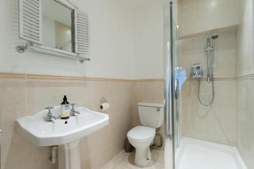 a bathroom with a toilet and a sink and a shower at The Mariners Suite in West Mersea