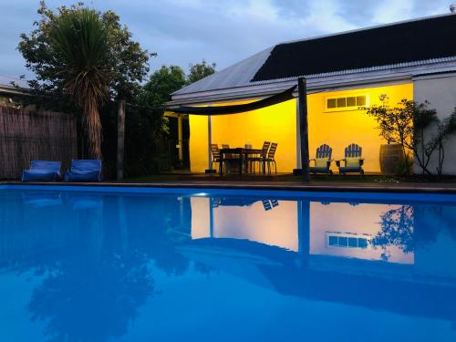 Casa con piscina con mesa y sillas en Woodstock Suite en Nelson