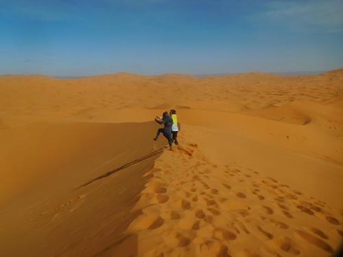 two people walking on a sand dune in the desert at Les Jardins De Todgha gorges de todra tinghir in Aït Baha