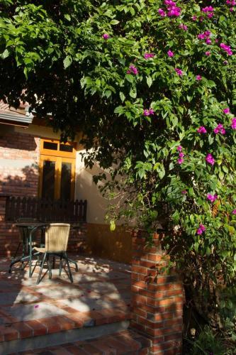 a table and a chair under a tree with pink flowers at Sitio dos Rochedos in Ivoti