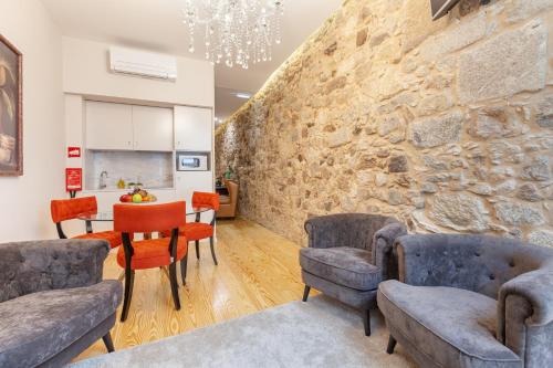 a living room with chairs and a stone wall at Berço de Mordomias in Braga