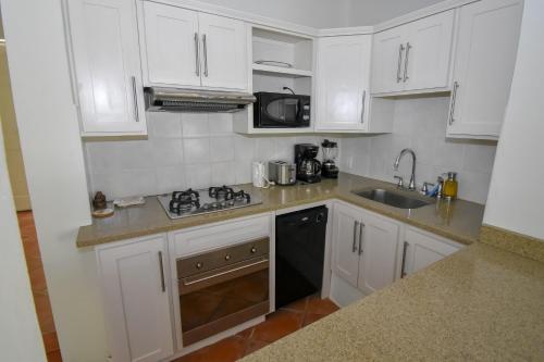 a small kitchen with white cabinets and a sink at Antigua Village Beach Resort in Saint Johnʼs