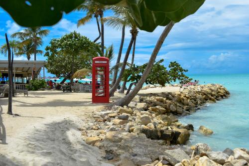 a red phone booth on a beach with palm trees at Antigua Village Beach Resort in Saint Johnʼs