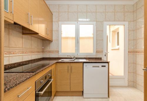 a kitchen with wooden cabinets and a white dishwasher at Residential jardín del pintor - la casa amarilla in Jacarilla