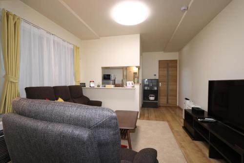 a living room with a couch and a television at Reussir Yamahanaminami 101 in Sapporo