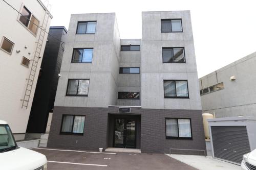 a tall building with a parking lot in front of it at Reussir Yamahanaminami 101 in Sapporo