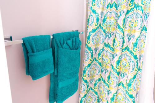 a bathroom with green towels and a shower curtain at Casa Victoria Golf Retreat in Caymanas
