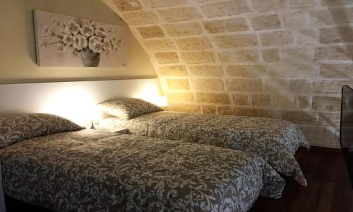 a bedroom with two beds and a stone wall at La Ginestra Affittacamere in Ginosa