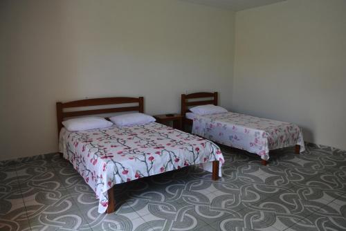 two beds sitting in a room with a carpet at Pousada Recanto Das Garças in Rio Preto Da Eva