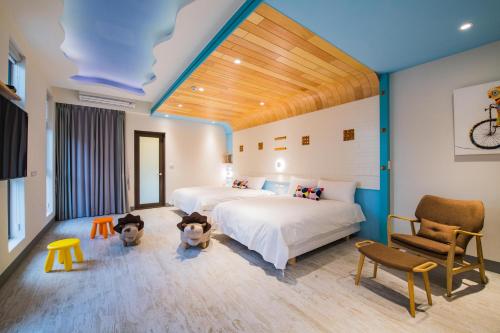 a bedroom with two beds and a chair at Happy Wing Guesthouse in Hualien City