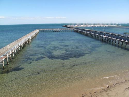 a pier in the water next to the beach at Brighton Bay Apartments in Melbourne