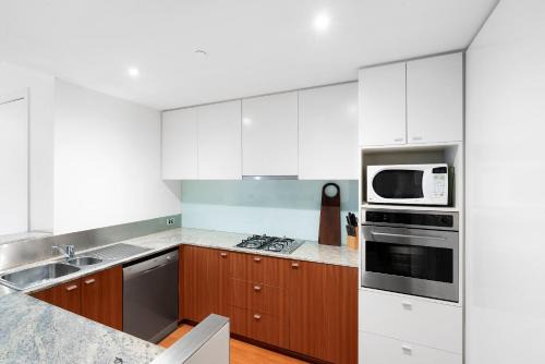 a kitchen with white appliances and wooden cabinets at Brighton Bay Apartments in Melbourne