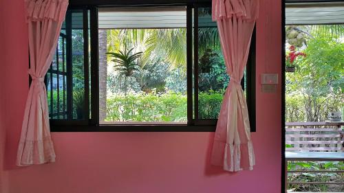 a room with a window with pink curtains at Warakorn Baansuan Amphawa in Amphawa