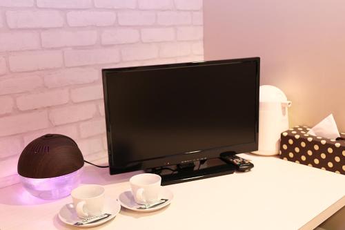 a computer monitor sitting on a desk with two cups at HOTEL 24sweets HAKUBA in Hakuba