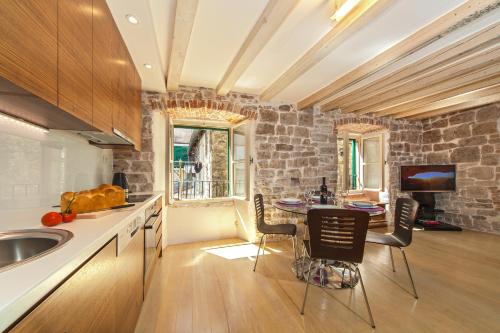 a kitchen with a table and a stone wall at Luxury San Giovanni Apartment 1 in Split