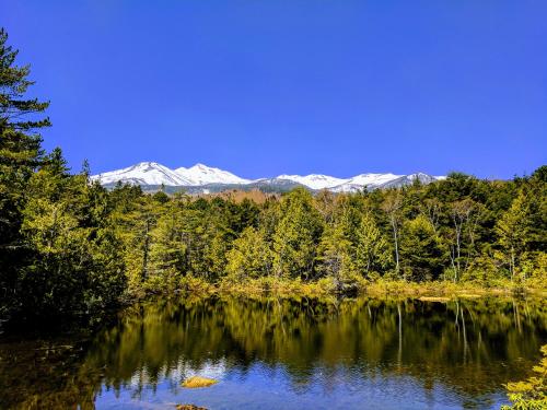 a lake with snow capped mountains in the background at NORTHSTAR Loft in Matsumoto