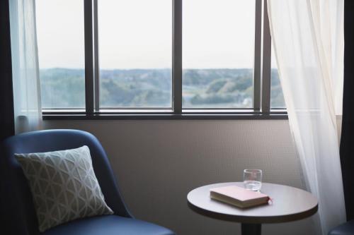 a room with a chair and a table with a glass at HOTEL MYSTAYS PREMIER Narita in Narita