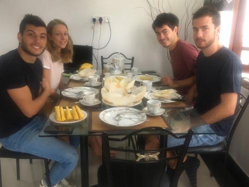 a group of people sitting around a table with food at Reshani Guest House in Negombo