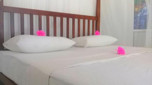 a bed with two pillows with pink tufty pillows at Mountain Heaven inn in Mirissa